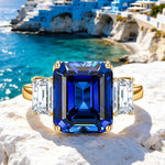 Emerald-Cut 5.5CT Royal Blue Lab-Grown Sapphire Engagement Ring – Three Stone Classic Design with Moissanite Side Stones, 14K Yellow Gold Plated on Tarnish-Resistant Silver（Includes GRC Certification from Gemstone Research Center）